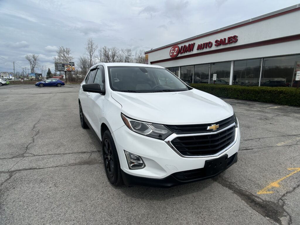 White Chevrolet SUV parked in a dealership lot in front of EZ LOAN AUTO SALES building.
