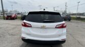Rear view of a white Chevrolet Equinox parked in a lot, with other vehicles in the background.