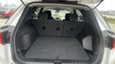 Open SUV hatch showing a large empty cargo area with rear seats upright and dark carpeting inside the trunk.