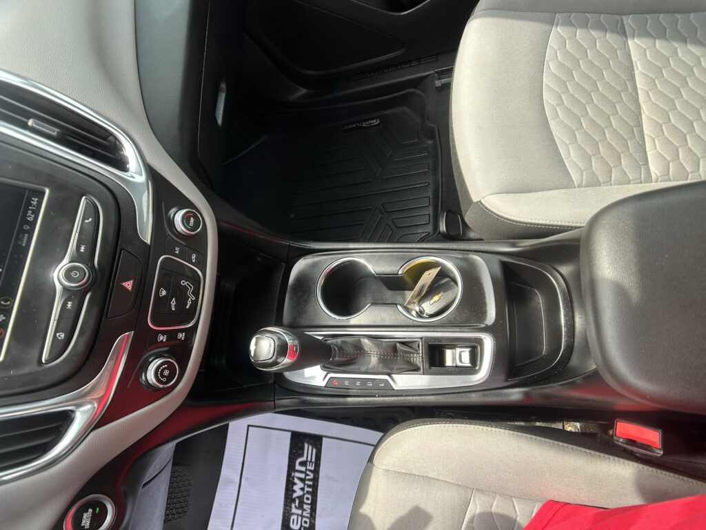 Interior of a car showing a center console with gear lever, cup holder, and storage area between front seats