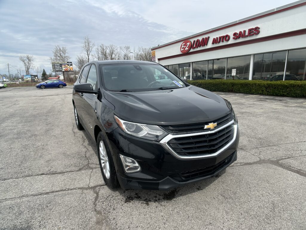 Black Chevrolet SUV parked in front of EZ Loan Auto Sales dealership; glossy finish and front grille visible in the lot