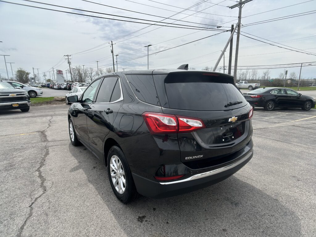 Black Chevrolet Equinox SUV parked in a dealership lot, rear three-quarter view.