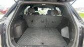 SUV/truck hatch open showing a large, empty cargo area with the rear seats upright and headrests visible in the back row, dark carpeted floor and trim