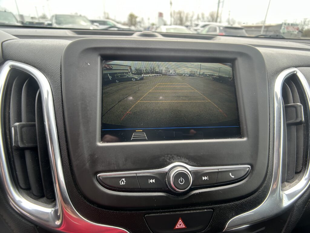 Rearview camera display showing a parking lot behind the car with orange guiding lines in the screen area.