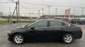 Black Chevrolet Malibu sedan parked in a wet parking lot with a red EZ Loan sign and power lines in the background.