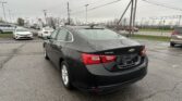 Black Chevrolet Malibu parked in a wet lot, rear view visible with rain droplets on the car.