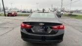 Rear view of a black Chevrolet Malibu parked in a wet parking lot on a rainy day, with the Chevy emblem and Malibu badge visible on the trunk.