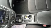 Front and center: automatic gear shifter, cupholders, and console with armrest in a car interior photographed from above/driver side.