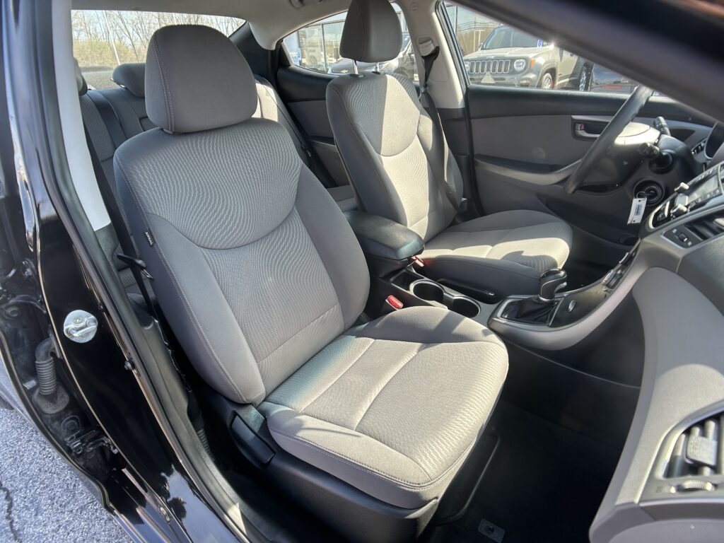 Front interior of a car with gray fabric seats, center console, and steering wheel visible.