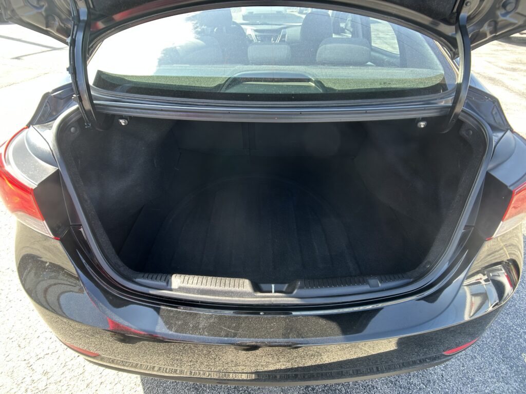 Open trunk of a black sedan with an empty cargo area and rear seats visible through the rear window.