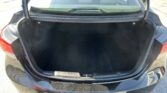 Open trunk of a black sedan with an empty cargo area and rear seats visible through the rear window.