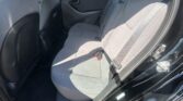 Interior of a car back seat with gray fabric upholstery and visible seat belts, front seats and door panel in view.