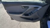 Interior of a car door panel with window controls and side mirror visible through the open window, in a parking lot curbside view