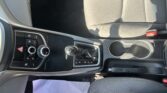 Car interior with gear shifter and climate controls; a white sheet of paper on the floor by the driver.