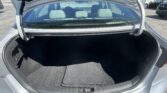 Open trunk of a silver sedan showing an empty cargo area with rear seats visible behind the glass window.
