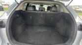 Trunk of an SUV with the rear seats upright, showing a spacious black cargo area outdoors in a parking lot.",