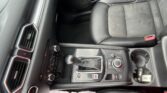 Center console area with gear shifter, climate controls, and cup holder in a dark car interior.