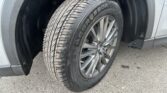 Close-up of a car tire mounted on a silver SUV wheel, showing treads and the surrounding wheel well on a paved surface