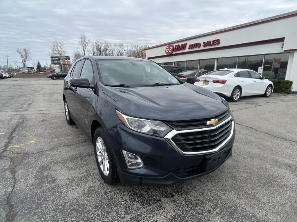 Dark gray SUV in the foreground of a dealership lot with the EZ Loan Auto Sales storefront in the background.