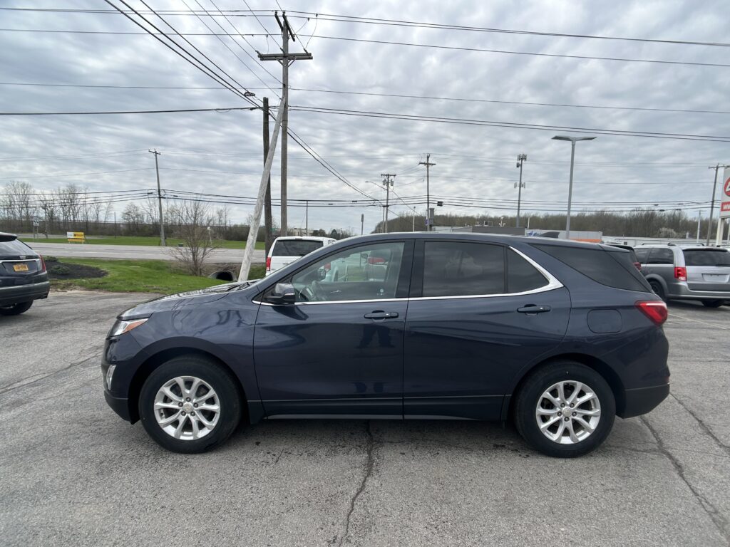 Blue SUV parked in a lot with other cars and overhead power lines in the background.