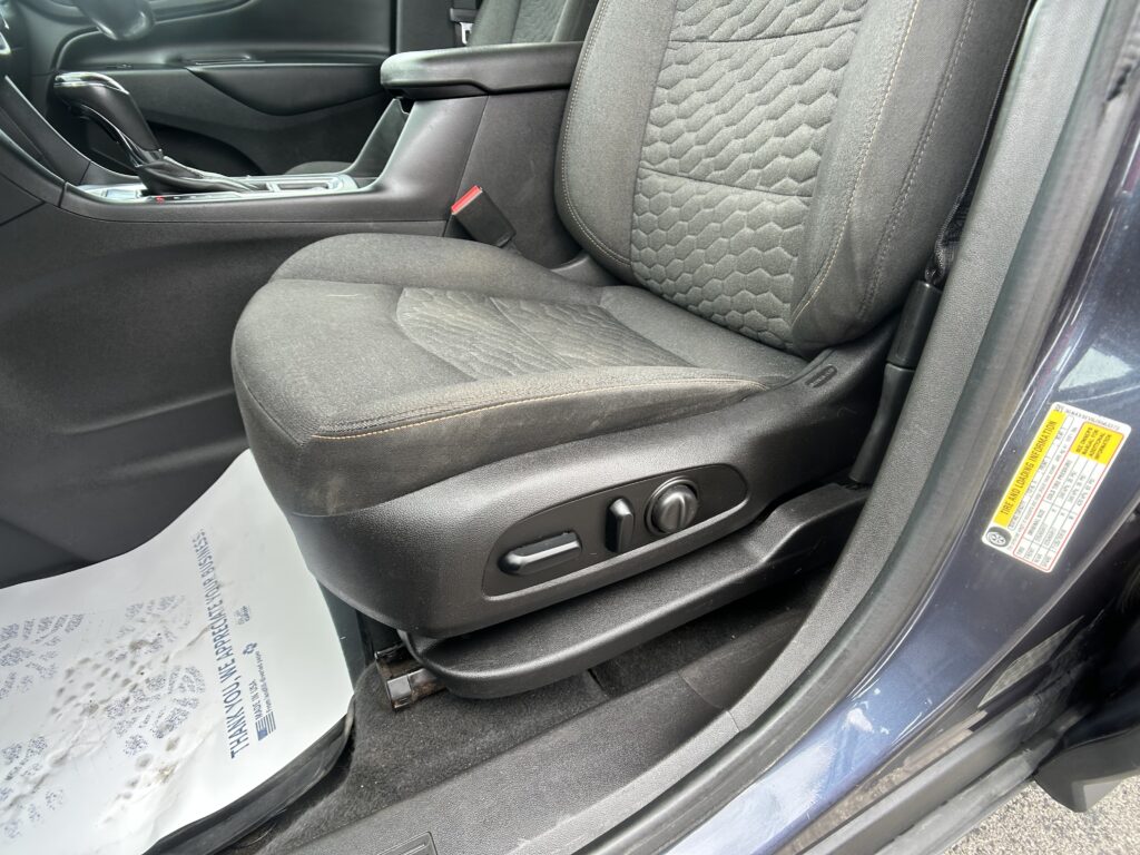 Interior of a car focusing on the front passenger area: center console, gear shifter, and dark fabric seats with stitched pattern visible.