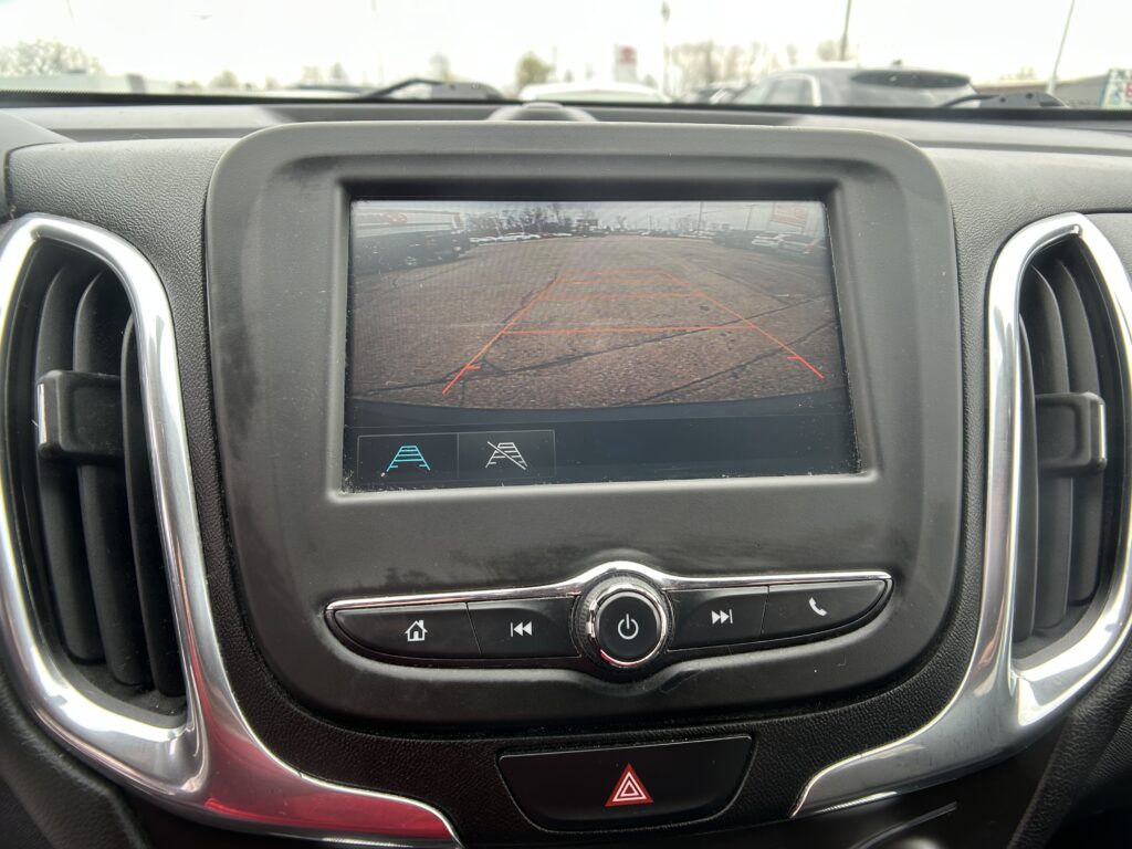 In-car display showing the rearview camera with orange parking guidelines to aid backing up; hazard light button below.