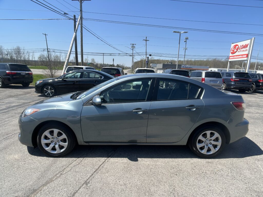 View of a car dealership lot with multiple parked cars under a clear blue sky; prominent EZ Loans Auto Sales sign on the right.