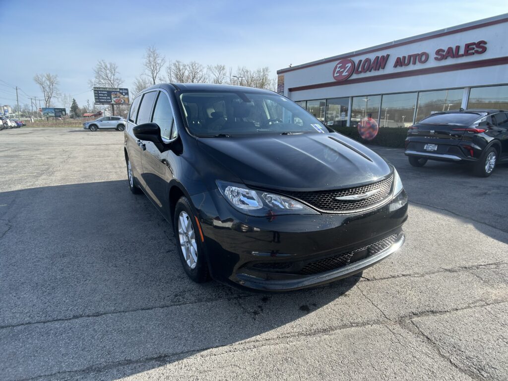 Black minivan parked in a dealership lot with the EZ LOAN AUTO SALES storefront in the background.