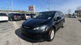 Front black minivan in a crowded car lot with a blue sky and an EZ LOAN Auto Sales sign in the background.