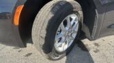 Close-up of a dark SUV wheel: tire, silver rim, and orange side marker light visible on the fender.