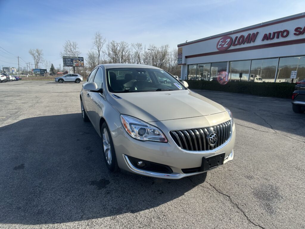 Silver Buick SUV parked in a lot with the EZ LOAN AUTO storefront visible to the right on a sunny day.