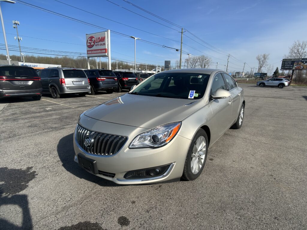 Silver Buick in the foreground at a car dealership lot with other vehicles and an EZ Loan Auto Sales sign against a blue sky.