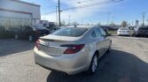 White Buick Regal in the foreground at a car dealership lot, with other cars and a Toyota sign in the distance.