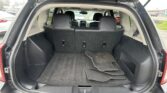Open SUV trunk showing cargo area with rear seats upright and black floor mats inside.