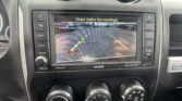Infotainment screen showing a rearview camera view with green/yellow/red guide lines and the message “Check Entire Surroundings!”