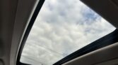 Open sunroof view showing a cloudy sky from inside a car interior