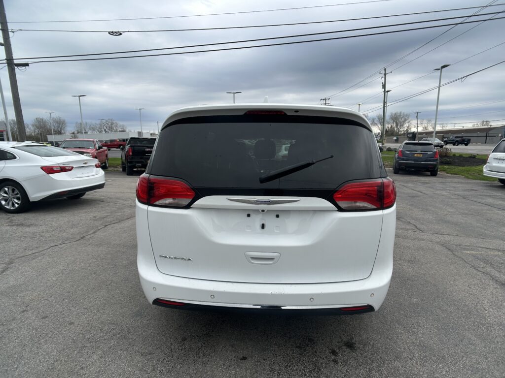 Rear view of a white Chrysler Pacifica in a parking lot on an overcast day with other cars nearby and power lines above.