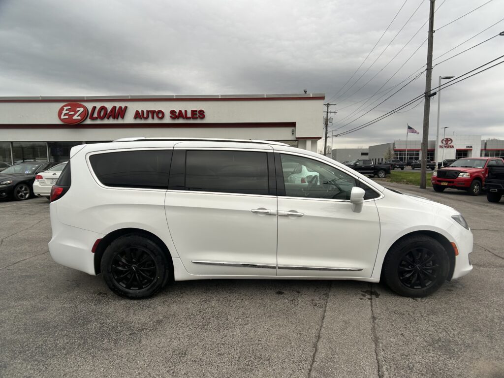 White minivan parked in front of E-Z Loan Auto Sales on a cloudy day.