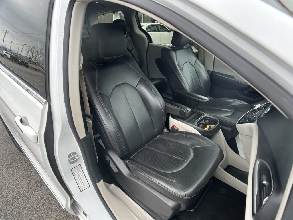 Inside view of a car with black leather front seats and red stitching, door open showing the vehicle’s interior.