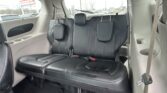 Black leather SUV rear seats with headrests, seat belts, and cupholders, view of parking lot through side windows