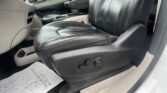 Leather car seats and center console viewed from the driver or front passenger side; gear area and door panel visible, with a disposable paper floor mat on the floor area