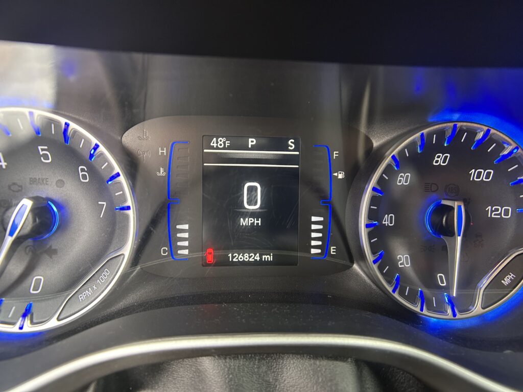 Car dashboard showing digital speedometer reading 0 MPH with an analog tachometer on the left and fuel/temperature gauges; odometer reads 126,824 miles.