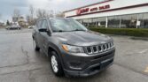 Gray Jeep SUV parked in a lot in front of an EZ Loan Auto Sales storefront under a cloudy sky.