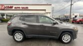 Gray Jeep Compass SUV parked in front of a used-car dealership with an "EZ LOAN AUTO SALES" sign on the building