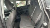 Back seat area of a dark fabric SUV interior with front seats and seat belts visible, rear doors open and exterior cars visible outside the window.