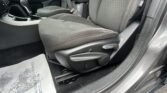 Interior of a car showing the front passenger seat, center console, and door frame; black fabric seats with white stitching and a patterned back panel.