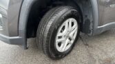Close-up of a gray vehicle's front wheel and wheel well with a snow-dusted tire surface.