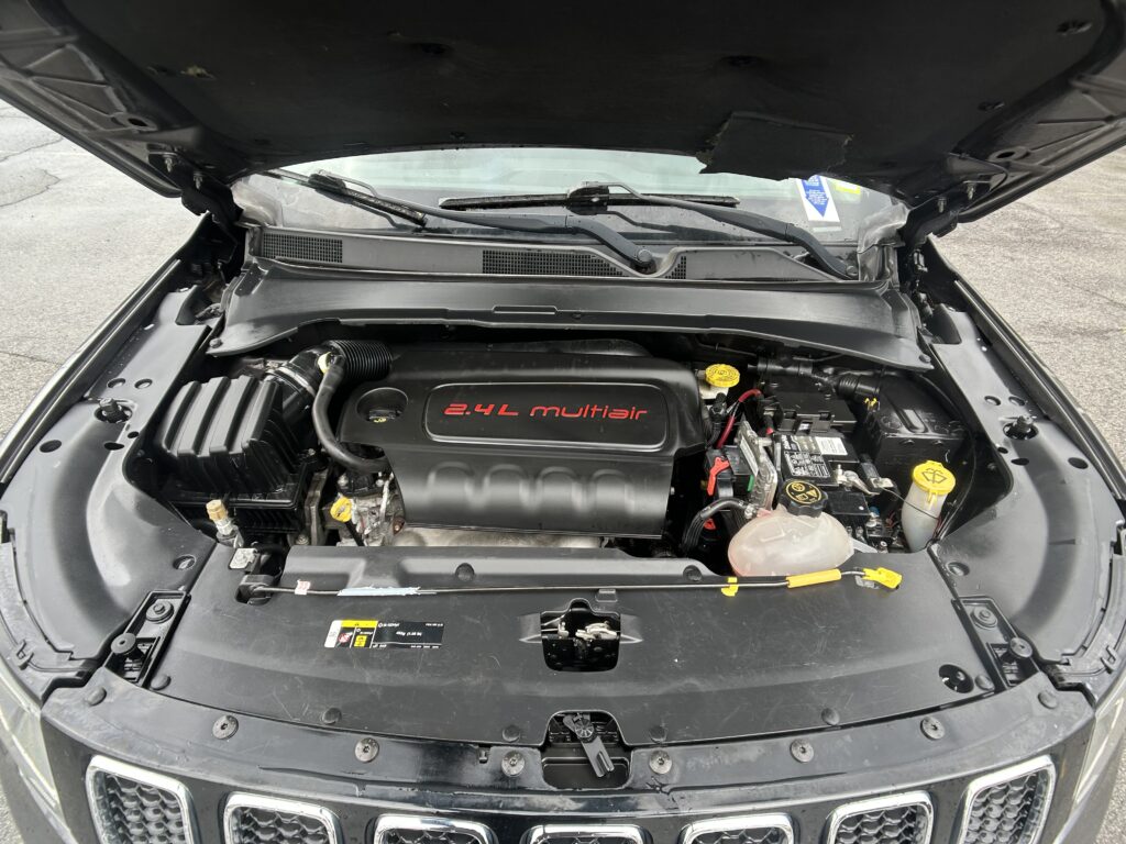 Open-hood view of a car engine bay, with the 2.4L Multiair badge on the engine cover visible at center front.