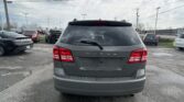 Rear view of a gray Dodge Journey in a parking lot with other cars and power lines overhead.