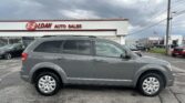 Gray SUV parked in front of a white auto dealership with a red E-Z LOAN sign and the words AUTO SALES, under a cloudy sky